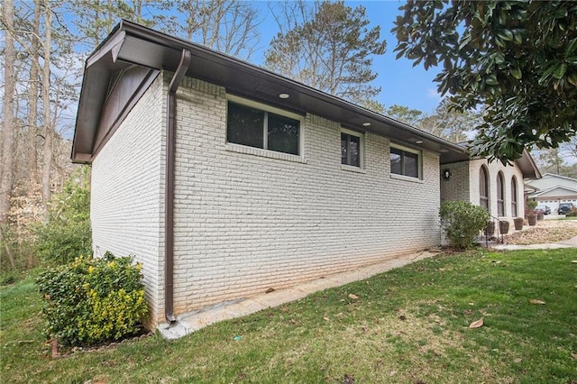 view of side of property featuring a lawn and brick siding