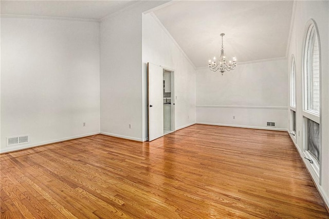 empty room with visible vents, wood finished floors, and ornamental molding