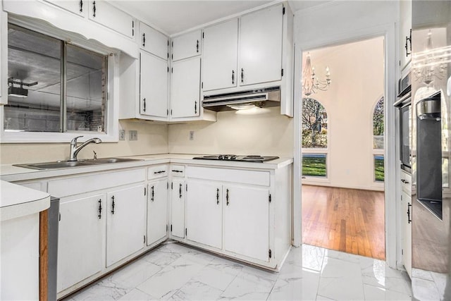 kitchen featuring marble finish floor, under cabinet range hood, a sink, white cabinetry, and light countertops