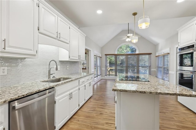 kitchen with appliances with stainless steel finishes, light wood-type flooring, tasteful backsplash, sink, and white cabinetry