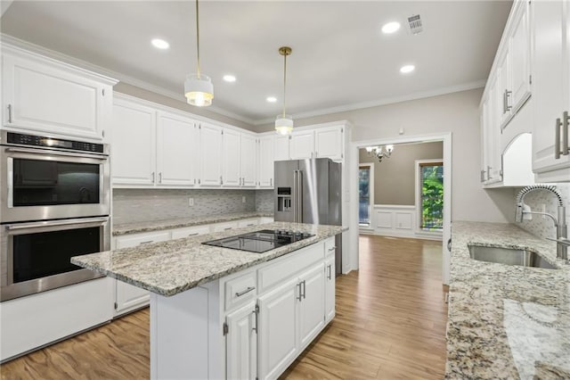 kitchen with white cabinets, sink, light hardwood / wood-style flooring, decorative light fixtures, and stainless steel appliances