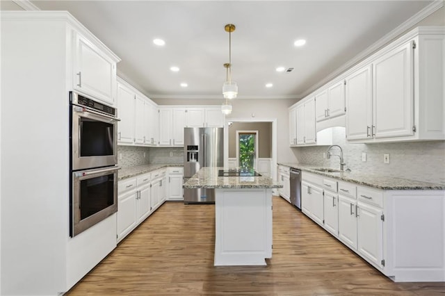 kitchen featuring appliances with stainless steel finishes, sink, decorative light fixtures, white cabinets, and a kitchen island