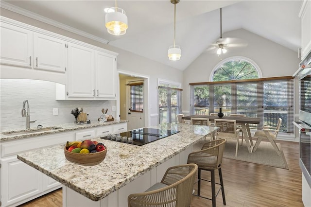 kitchen with black electric cooktop, ceiling fan, white cabinets, and hanging light fixtures