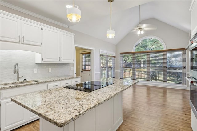 kitchen featuring stainless steel appliances, a kitchen island, pendant lighting, stone countertops, and white cabinets