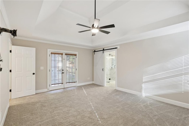 unfurnished bedroom featuring a tray ceiling, multiple windows, ensuite bathroom, and ceiling fan