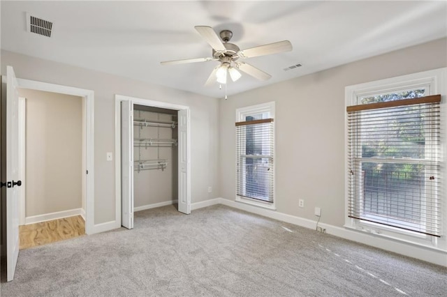 unfurnished bedroom featuring ceiling fan, a spacious closet, ensuite bathroom, light colored carpet, and a closet