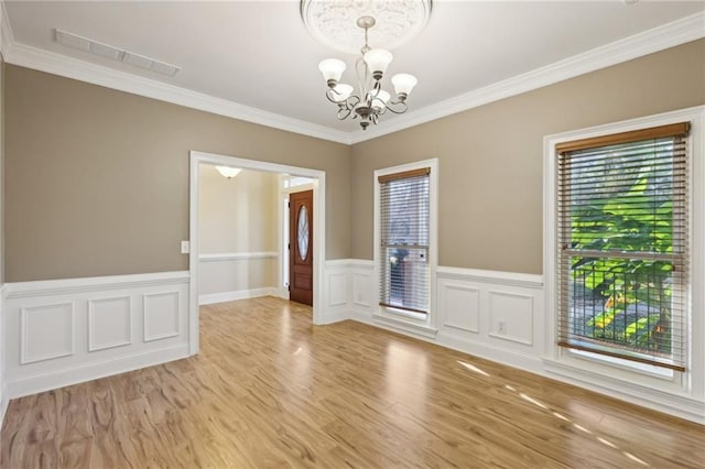 empty room featuring a notable chandelier, light hardwood / wood-style floors, and crown molding