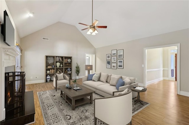 living room with ceiling fan, high vaulted ceiling, and light hardwood / wood-style flooring