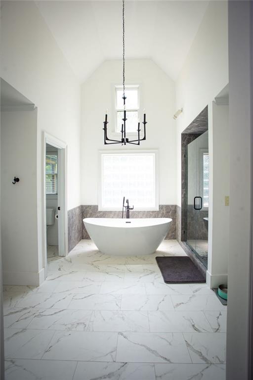 200 Carney Ct, Ball Ground, GA 30107 - bathroom featuring a freestanding bath, high vaulted ceiling, a notable chandelier, and marble finish floor