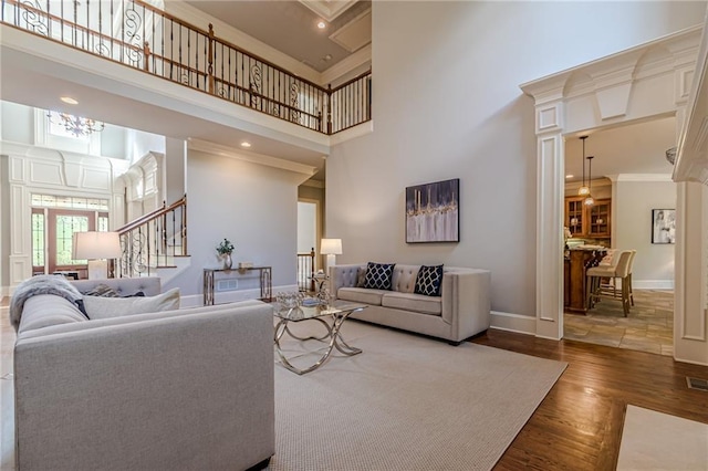 living room with a high ceiling, crown molding, and hardwood / wood-style floors