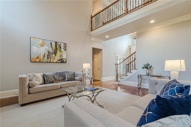 living room featuring an inviting chandelier, crown molding, hardwood / wood-style flooring, and a high ceiling