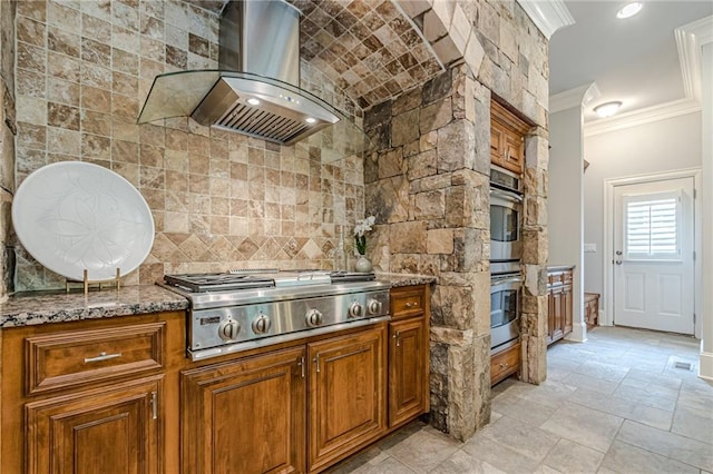 kitchen featuring crown molding, ventilation hood, dark stone counters, and appliances with stainless steel finishes