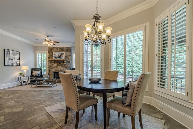 dining space with crown molding, a stone fireplace, and ceiling fan with notable chandelier