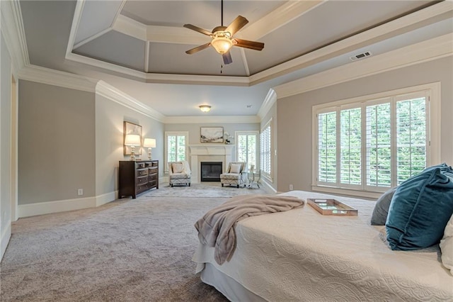 carpeted bedroom with crown molding, a tray ceiling, and ceiling fan