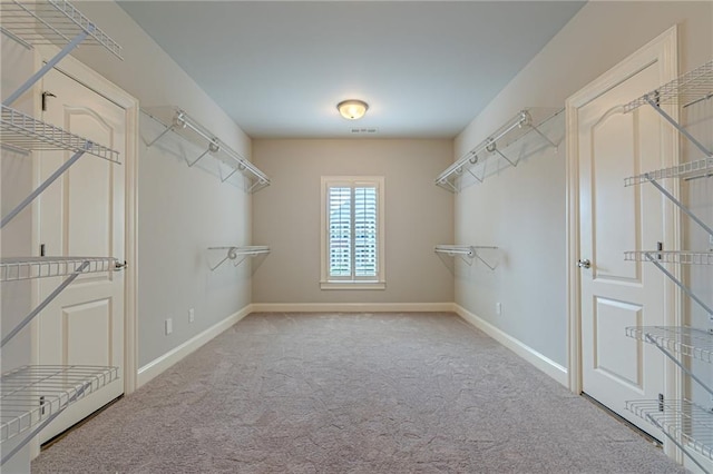 walk in closet featuring light colored carpet