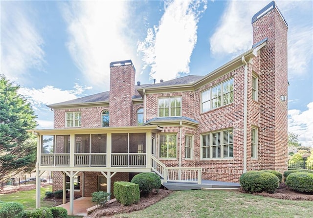 back of property with a sunroom, a patio area, and a lawn