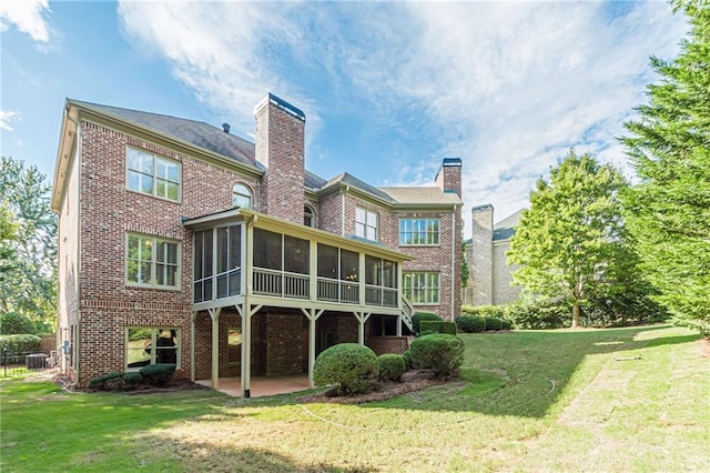 back of property with a sunroom, a yard, and a patio area