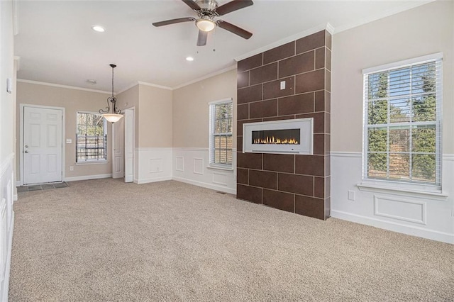 unfurnished living room featuring crown molding, a tile fireplace, and carpet