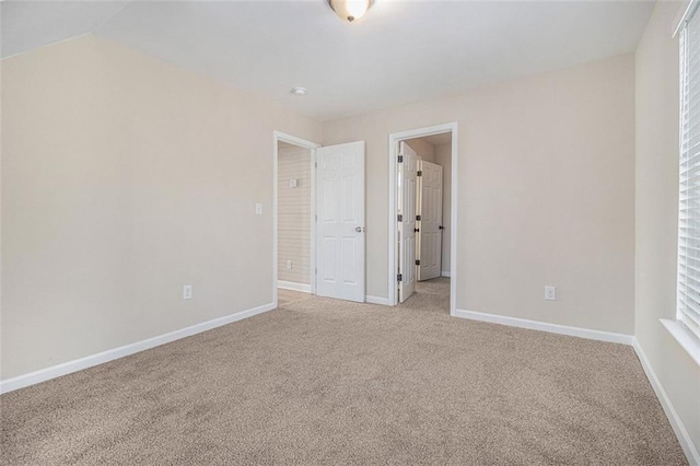 carpeted spare room featuring vaulted ceiling