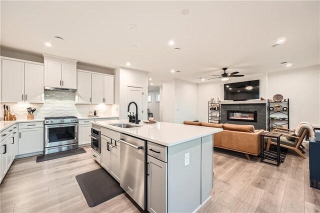 kitchen featuring under cabinet range hood, light countertops, decorative backsplash, high end range, and white cabinets