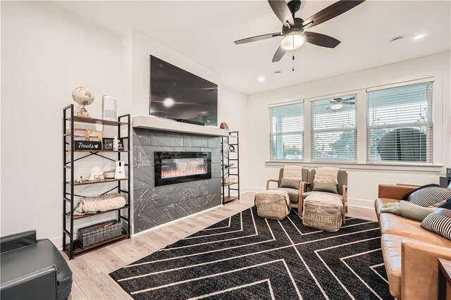 living room with baseboards, recessed lighting, wood finished floors, a glass covered fireplace, and a ceiling fan