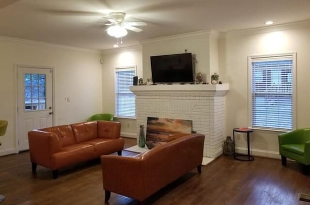 living room featuring crown molding, a brick fireplace, hardwood / wood-style floors, and ceiling fan