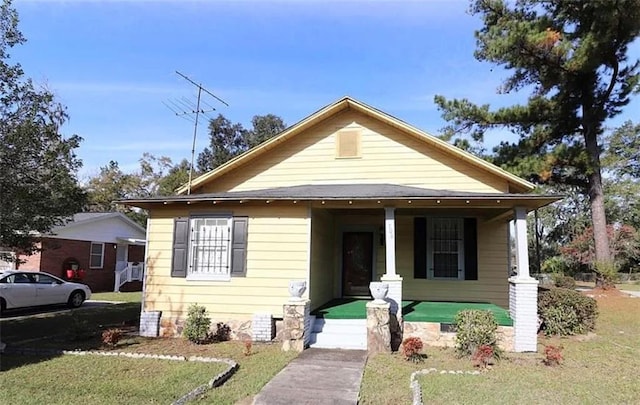 bungalow featuring covered porch and a front lawn