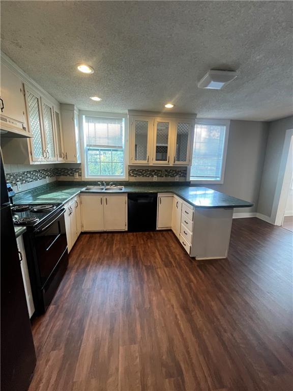 kitchen featuring tasteful backsplash, black appliances, white cabinets, dark hardwood / wood-style flooring, and kitchen peninsula