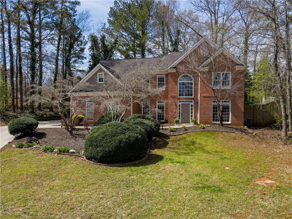 view of front of property featuring brick siding, a front yard, and fence