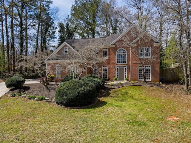 view of front of property featuring brick siding, a front yard, and fence