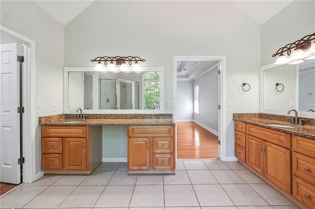 full bath with two vanities, high vaulted ceiling, a stall shower, and a sink