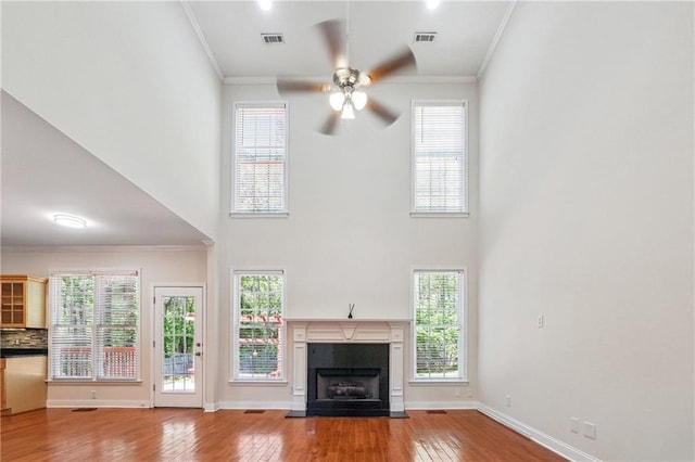 unfurnished living room featuring a fireplace with flush hearth, ceiling fan, crown molding, and hardwood / wood-style floors