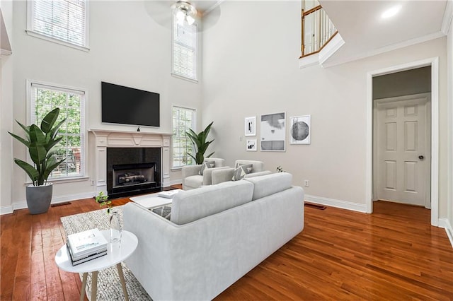 living area with a fireplace with flush hearth, baseboards, a healthy amount of sunlight, and hardwood / wood-style flooring