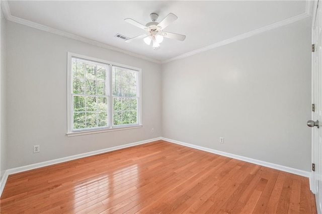 empty room featuring baseboards, light wood-style flooring, visible vents, and crown molding