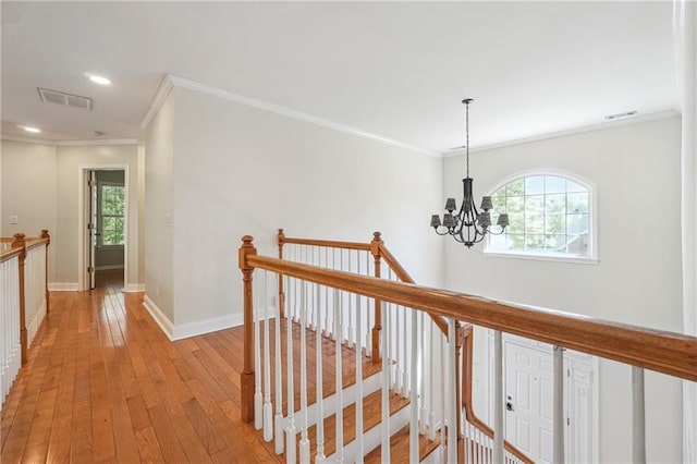 hall featuring visible vents, ornamental molding, an upstairs landing, a wealth of natural light, and a chandelier