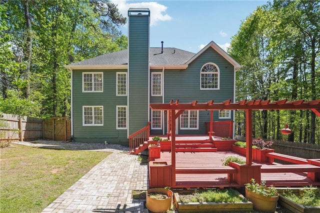 rear view of house with a chimney, a fenced backyard, a yard, a patio, and a garden