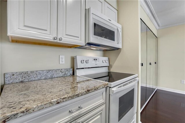 kitchen with light stone counters, dark hardwood / wood-style floors, white cabinetry, crown molding, and white appliances