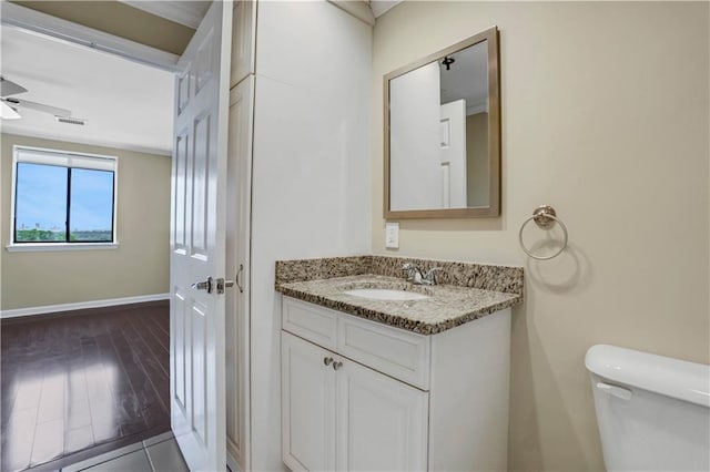 bathroom with hardwood / wood-style floors, vanity, ceiling fan, and toilet