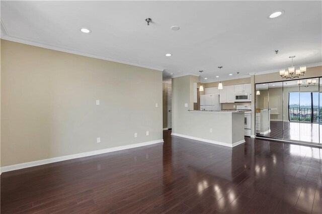 unfurnished living room with dark hardwood / wood-style floors, ornamental molding, and an inviting chandelier