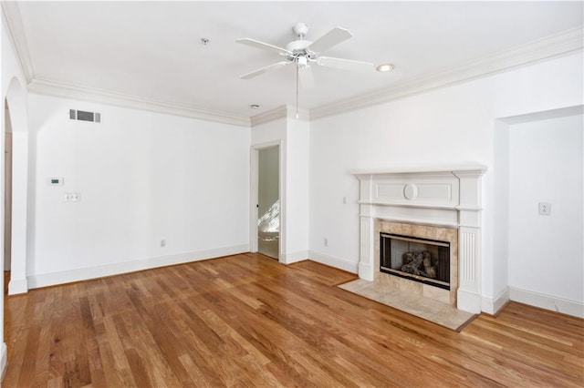 unfurnished living room featuring ceiling fan, crown molding, a tiled fireplace, and hardwood / wood-style floors