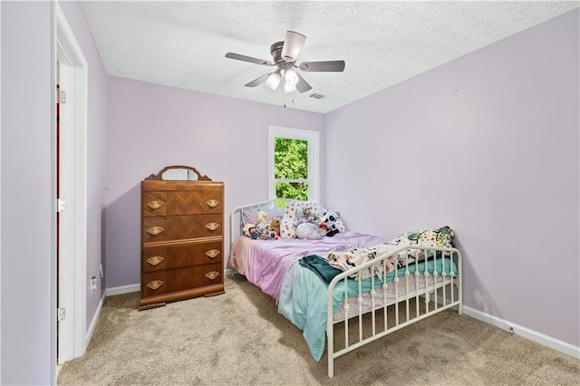 carpeted bedroom featuring baseboards, a ceiling fan, and a textured ceiling