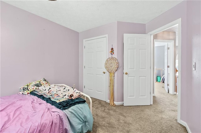 bedroom featuring light carpet, baseboards, and a textured ceiling
