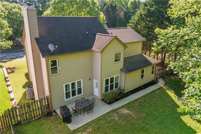 back of property featuring a chimney, a patio area, roof with shingles, and central AC unit