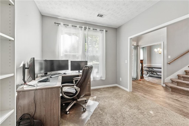 office with light colored carpet, baseboards, a textured ceiling, and light wood-style flooring