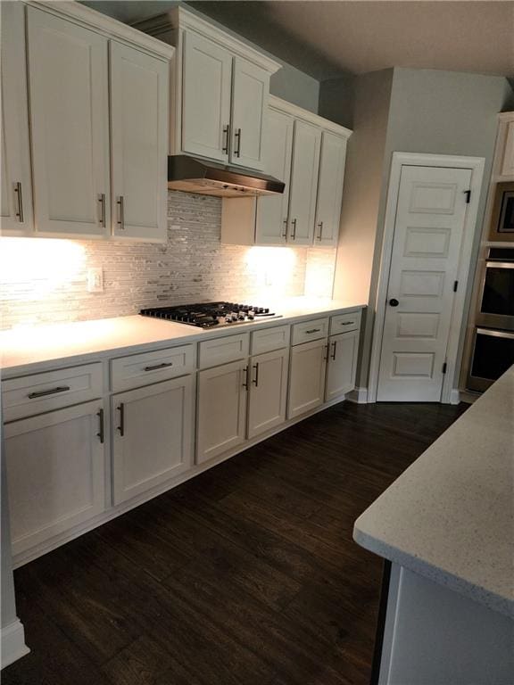 kitchen featuring white cabinets, appliances with stainless steel finishes, dark wood-type flooring, and tasteful backsplash