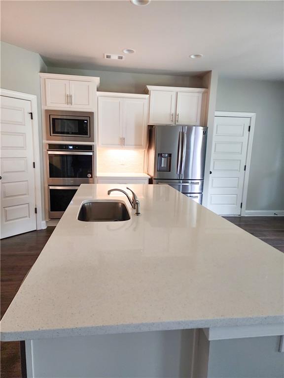 kitchen featuring a center island with sink, white cabinetry, sink, and stainless steel appliances