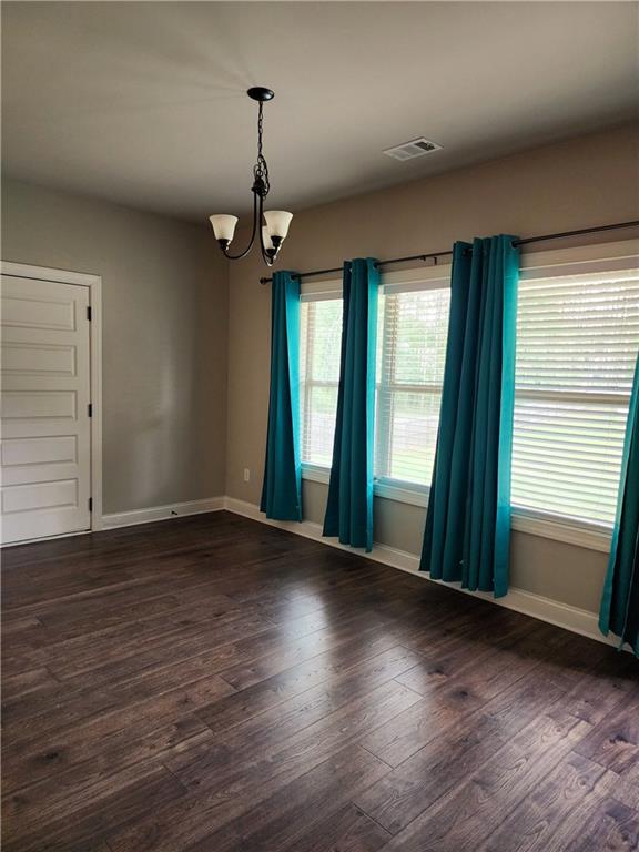 empty room featuring a chandelier and dark hardwood / wood-style flooring