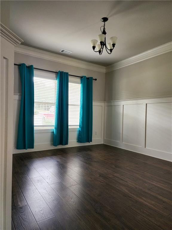 empty room featuring an inviting chandelier, ornamental molding, and dark hardwood / wood-style floors