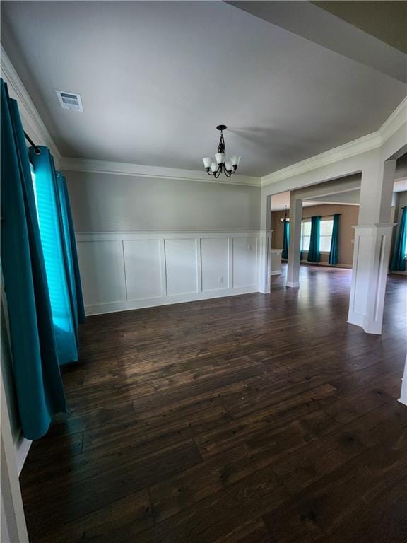 unfurnished living room featuring dark hardwood / wood-style floors, ornamental molding, and an inviting chandelier