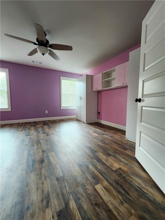 empty room featuring ceiling fan, plenty of natural light, and dark hardwood / wood-style flooring